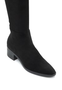 Must musta knee-high saapad terava varbaga ja ploki kontsaga. Sile tekstuur koos liibuva varsiga. Ilma kaunistuste või mustriteta.