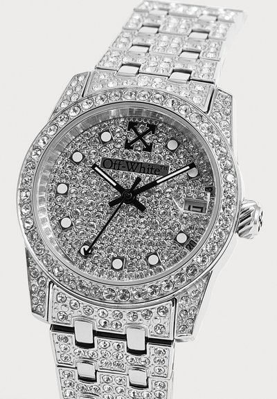 Montre-bracelet de luxe argentée incrustée de cristaux sur le cadran, la lunette et le bracelet, avec des aiguilles noires, une fenêtre de date et un marquage Off-White sur le cadran.