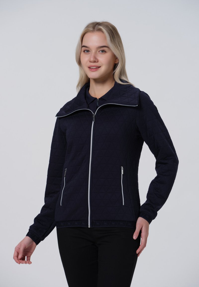 Veste matelassée bleu marine avec col montant, fermeture éclair à l'avant et deux poches latérales. Présente des motifs triangulaires et des poignets élastiques.