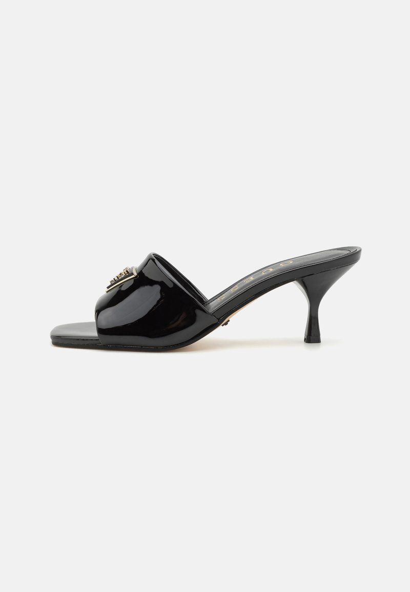 Black patent leather open-toe mules featuring a small structured heel, a smooth texture, and a decorative metallic accent on the front.