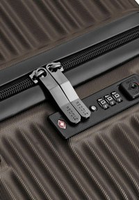 Deux tirettes de fermeture éclair verrouillées dans un cadenas à combinaison approuvé par la TSA sur une valise rigide texturée.