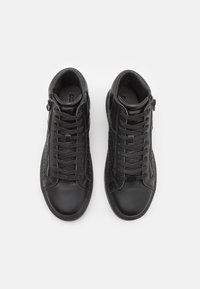 Sneakers alte nere con pannelli laterali testurizzati, lacci piatti e cerniere esterne. Pelle liscia e suola in gomma, design minimalista.