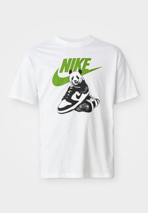 White cotton t-shirt featuring a black-and-white panda graphic holding a Nike sneaker, with a green Nike logo above.