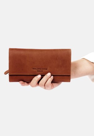 Brown leather wallet with a smooth texture, bi-fold design, and a logo embossed on the front. Hand-held against a neutral background.