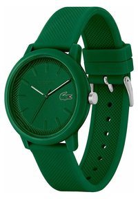 Montre-bracelet en silicone vert avec un cadran texturé, des aiguilles argentées et le logo Lacoste. Boîtier rond et bracelet ajustable avec perforations.