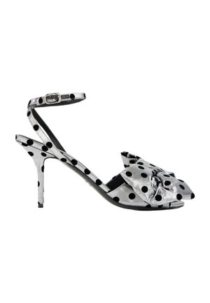 Sandale à talons hauts argentée avec des pois noirs, bride cheville avec boucle et un grand détail nœud sur les orteils.