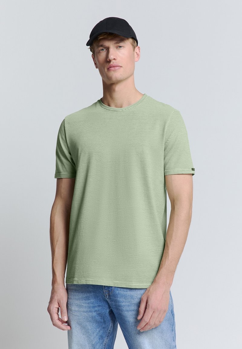 Lichtgroen T-shirt met korte mouwen, horizontale strepen, ronde hals en zwart accent op de mouw, gecombineerd met lichtblauwe jeans.