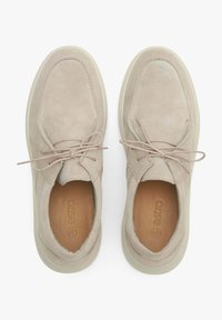 Beżowe zamszowe buty o gładkiej fakturze, okrągłym nosku i jasnej podeszwie. Charakteryzują się prostym wzorem sznurowania oraz haftowanymi detalami.