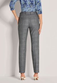 Grau karierten Stoffhosen mit geradem Schnitt, aus einem strukturierten Material gefertigt. Mit Gürtelschlaufen und Taschen, kombiniert mit cremefarbenen Absatzschuhen.