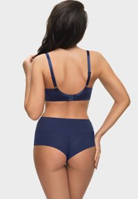 Navyblauer BH und hochgeschnittener Slip im Set. Glattes Material mit einem strukturierten Einsatz am Slip. Verstellbare Träger und Hakenverschluss am BH.