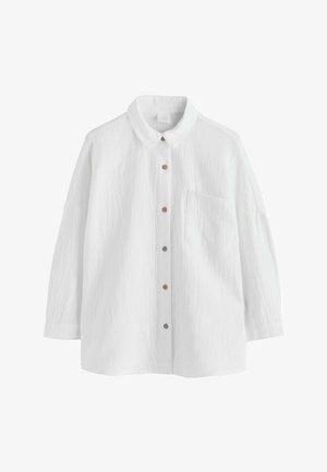 Cămașă albă cu mâneci lungi și nasturi, cu buzunar frontal și nasturi maro, având o croială lejeră și țesătură texturată.