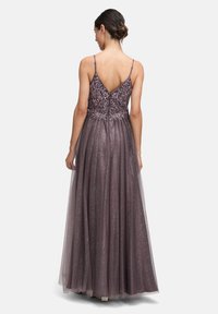 Długa, bezrękawna suknia w przygaszonym mauve z dopasowanym beaded topem i zwiewną, przezroczystą spódnicą ozdobioną subtelnym blaskiem. Design z tyłem w kształcie litery V.