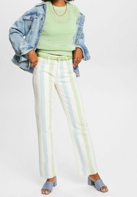 Jasnozielony, dziany sweter, jasnoniebieska kurtka dżinsowa, pastelowe, paskowane spodnie z szerokimi nogawkami oraz jasnoniebieskie mule na blokowym obcasie.
