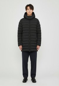 Black puffer jacket with a high collar, zipper closure, and two side pockets. Features a quilted design and a slim fit cut.