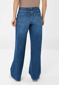 Blauwe denim jeans met wijde pijpen en een middellange taille, voorzien van twee achterzakken en een nette zoom. De stof heeft een gladde, gelijkmatige textuur.