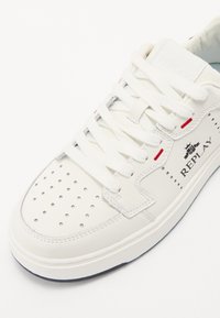 Weißer Ledersneaker mit durchlöchtem Zehenbereich, weißen Schnürsenkeln und roten Akzentdetails. Mit dem "REPLAY"-Logo an der Seite präsentiert.