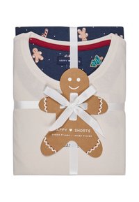 Kremowy komplet piżamowy z granatowym wzorem z pierniczkami. Owinięty białą wstążką z zawieszką w kształcie pierniczka.