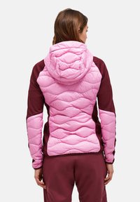 Giacca imbottita con un davanti trapuntato rosa, maniche bordeaux e cappuccio. Presenta una texture e un motivo di cucitura a contrasto.