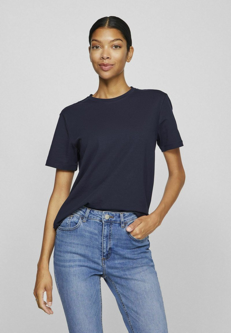 Marineblå bomulls t-skjorte med kort erm, rund hals og avslappet passform, kombinert med lyseblå denimjeans.