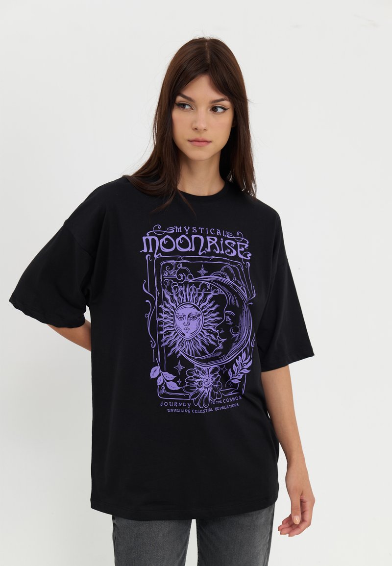 Black oversized cotton t-shirt featuring a purple graphic design of a sun and moon, with decorative floral elements and text.