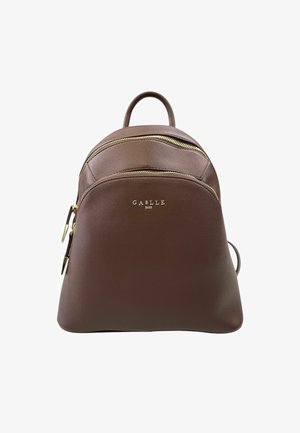 Zaino in pelle marrone con forma arrotondata, dettagli in metallo dorato, scomparti con doppia zip e logo impresso sul fronte.