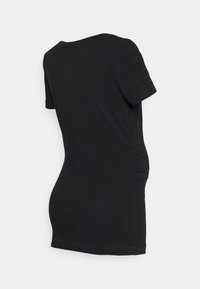 T-shirt preto de manga curta com decote arredondado, apresentando detalhes franzidos nas laterais para um efeito texturizado. Tecido de algodão suave.