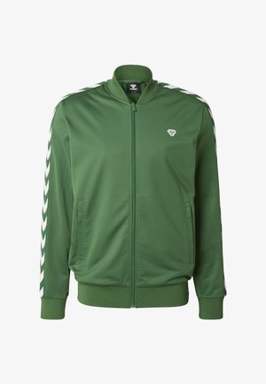 Groene jas met ritssluiting, gemaakt van gladde stof, met witte chevronstrepen op de mouwen en een klein logo op de borst. Twee zijzakken.