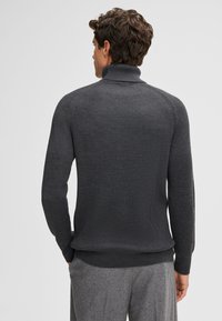 Dunkelgrauer gerippter Rollkragenpullover mit langen Ärmeln und figurbetontem Design, ausgestattet mit einem nahtlosen Finish und strukturiertem Strickmuster.