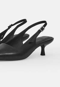 Black leather slingback shoes with a pointed toe and low, slender heel; features an adjustable strap with a silver buckle detail.