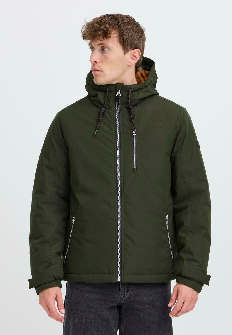 Giacca isolante verde con cappuccio, dotata di una cerniera frontale, tasche laterali con cerniera e una texture morbida. Accentuata con rivestimenti marroni.