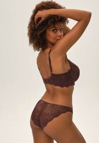 Brązowy biustonosz koronkowy i pasujące majtki charakteryzują się falbaniastymi krawędziami, kwiatowym wzorem, regulowanymi ramiączkami i delikatną teksturą.