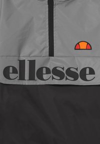 Jasnoszary wiatrówka z czarnym pasem z logo "ellesse", zamek błyskawiczny z przodu oraz kolorowym akcentem w kształcie półokręgu na klatce piersiowej.
