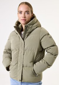 Chaqueta acolchada en verde oliva claro, cuenta con una capucha, cierre frontal con cremallera, puños elásticos y bolsillos laterales con un acabado suave y texturizado.