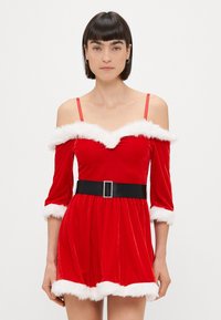 Rdeča žametna obleka z odkrito rameni in belim umetnim krznom, s rokavi do tri četrtine in črnim pasom z srebrno zaponko. Kratka dolžina.