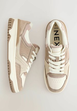 Beige ja kreem värvi sneaksid, mis on valmistatud nahast ja suededest materjalidest, millel on perforatsiooniga varvas, lamead ja pehme kaelus ja keel.