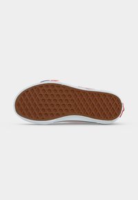 Καφέ λαστιχένια σόλα sneaker με σχέδιο βάφλας και λευκή ενδιάμεση σόλα, τοποθετημένη επίπεδα σε ανοιχτό φόντο.