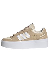 Adidas lenkkarit vaaleanbeige ja valkoinen, paksu valkoinen pohja, valkoiset raidat sivuilla, vaaleanbeige nauhat ja kultainen Adidas-logo kantapäässä.