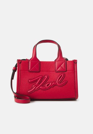 Bolso de mano de cuero rojo con textura granulada, con asas cortas y una correa de hombro ajustable. El logo "Karl" está bordado de manera prominente.
