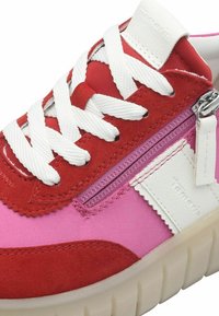 Rosa und rote Sneaker mit weißen Schnürsenkeln, die ein Reißverschlussdetail und strukturiertes Wildleder aufweisen. Die Sohle ist dick und halbtransparent.