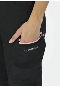 Svarta byxor med en rosa dragkedjeficka och "SWEDEMOUNT"-logotyp. Tyget har en jämn textur och är designat för funktionell användning.