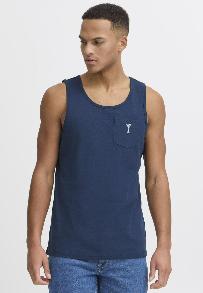 Jūras spēku zila bezceļa krekls, izgatavots no mīksta auduma, ar apaļu kakla izgriezumu un krūšu kabatu, kurā ir izšūts kokteiļa glāzes motīvs.