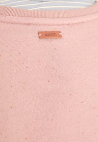 Tessuto di cotone rosa con piccole macchie multicolori, caratterizzato da un collo rotondo e un'etichetta in pelle marrone cucita sul retro.