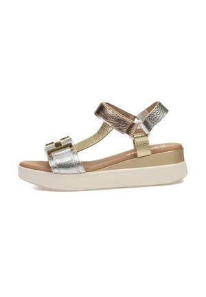 Sandal metálico de tres tiras con una suela blanca gruesa, cuenta con acentos en plata, oro y bronce, y una superficie texturizada en las tiras.