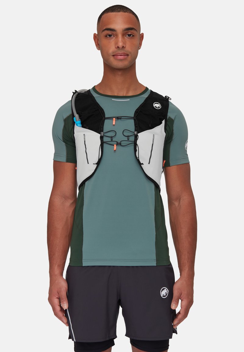 Black and gray hydration vest worn over a green athletic shirt, featuring a front pocket, adjustable straps, and water tube attachment.