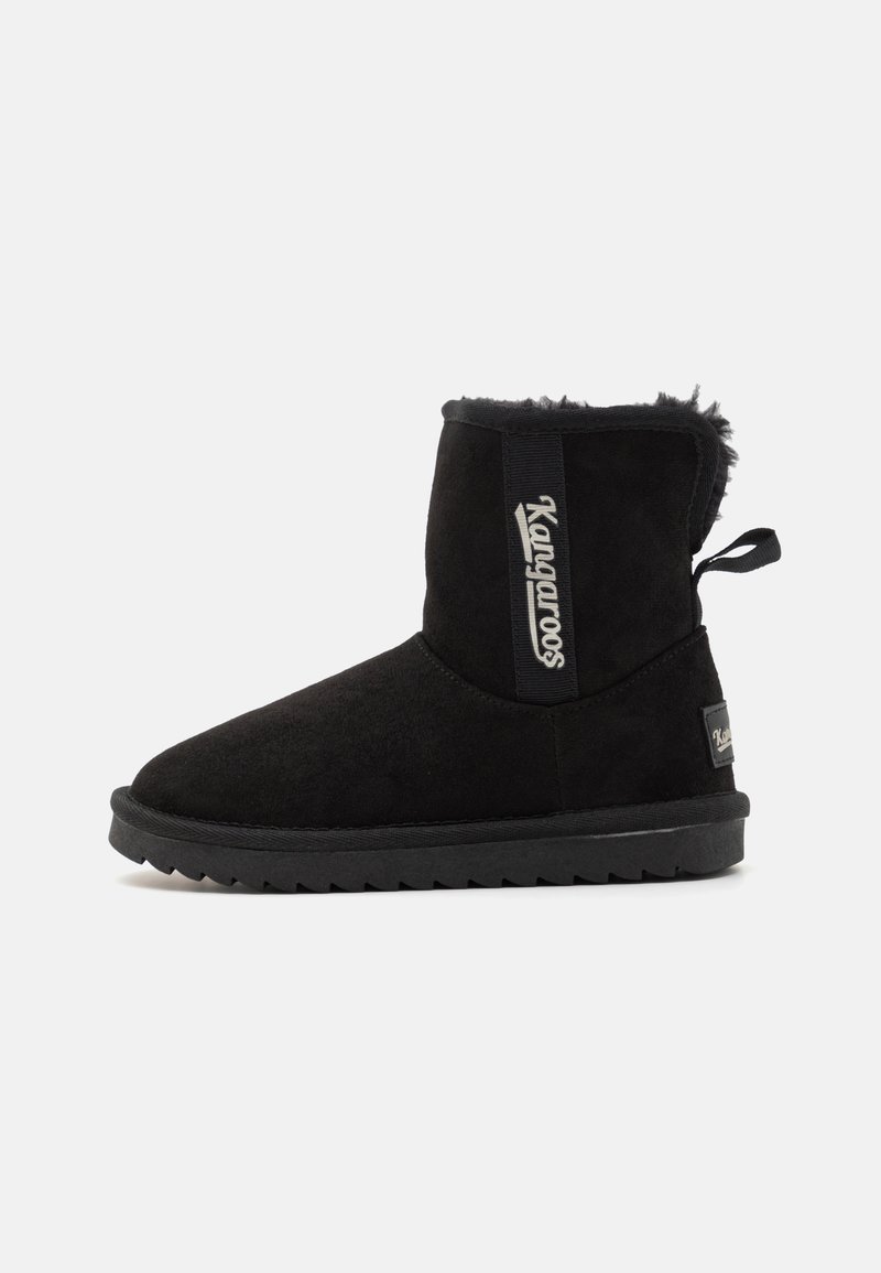 Botas de tornozelo em camurça preta com parte superior texturizada, forro interior suave e sola de borracha plana. Possui uma etiqueta com o logótipo e uma alça de puxar.