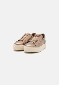 Sneakers bronzo metallico con una finitura liscia, design con lacci, cerniera laterale e una suola piatta bianca robusta. Presenti dettagli testurizzati.