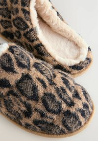 Leopard print slippers made of soft fabric with a furry lining, featuring a rounded shape and textured black and tan pattern.