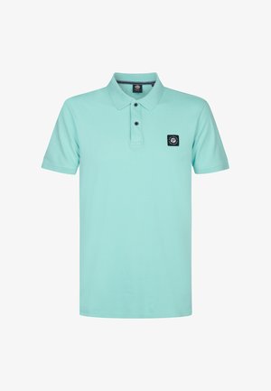 Vaaleansininen puuvillapolo-paita, jossa on kaulus, kolme nappia ja musta neliölogo vasemmassa rinnassa. Lyhyet hihat, rento malli.