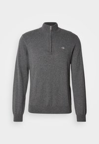 Pull en maille gris foncé à manches longues avec une fermeture éclair au quart et un petit logo brodé sur la poitrine gauche.