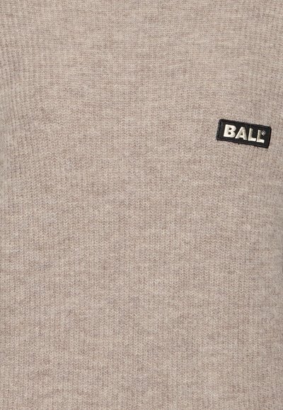Beige pletený svetr s texturovaným vzorem; má černou etiketu s bílým textem "BALL." Měkká textilie.